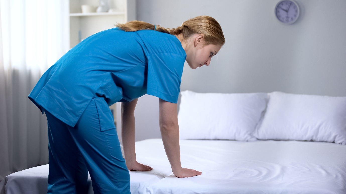 Nurse preparing clean bed-linen to patient in medical center